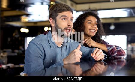 Male and female fans celebrating team victory, watching sport competition online Stock Photo