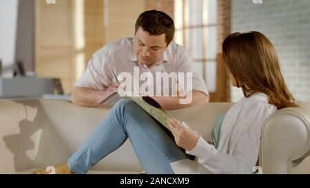 Young happy couple planning vacation trip together, choosing place on map Stock Photo