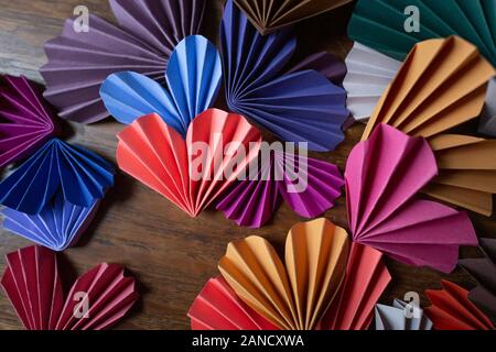 Multi-colored paper origami hearts arranged on wooden background Stock Photo