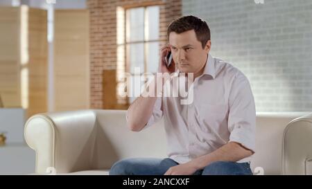 Young handsome businessman having serious phone conversation with partner Stock Photo