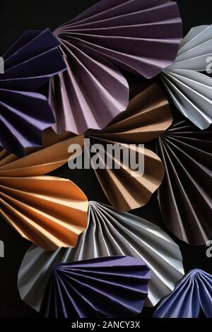 Folded colorful origami hearts arranged against dark background Stock Photo