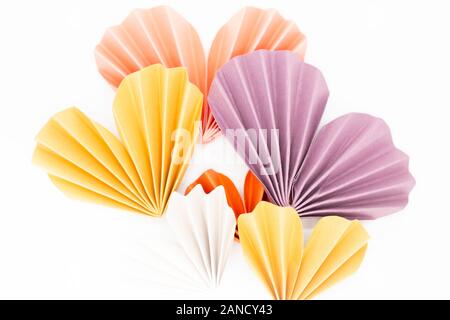 Purple, yellow, and orange colored paper hearts on white background Stock Photo
