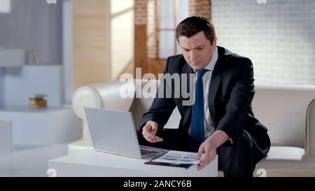Young businessman checking financial report, working on laptop in modern office Stock Photo