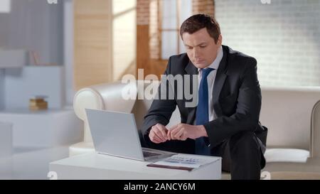 Young financier checking company report, working on laptop in modern office Stock Photo