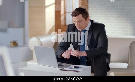 Young businessman working on laptop in apartment, managing company remotely Stock Photo