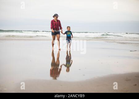 mother walking on beach, holding hands with her son. Stock Photo