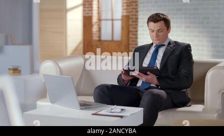 Well-dressed man using tablet in office, modern technologies to manage business Stock Photo