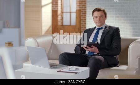 Young man in suit using tablet in office, modern technologies to manage business Stock Photo