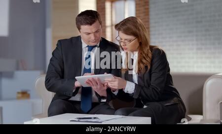 Colleagues planning startup on tablet together, discussing business issues Stock Photo