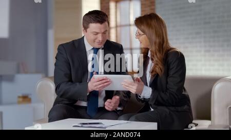 Business colleagues discussing startup strategy, watching project on tablet Stock Photo