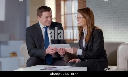 Excited business partners laughing, holding tablet with online startup project Stock Photo
