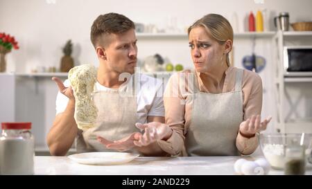 Master chef stretching raw dough, dissatisfied with work of new cook, profession Stock Photo