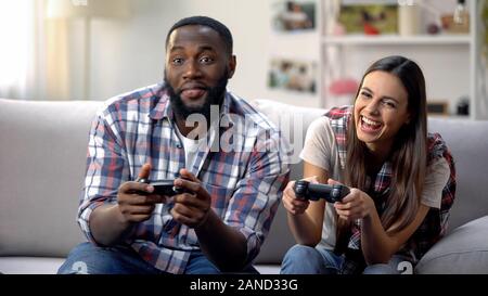 Laughing mixed-race family having fun, playing video game at home, leisure time Stock Photo