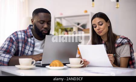 Multiethnic couple of freelancers working together at home using computer, job Stock Photo