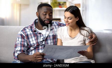Smiling lady and black man planning interior design of new house, crediting Stock Photo