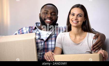 Happy mixed-race couple holding carton boxes, ready to move in new apartment Stock Photo