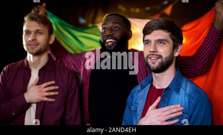 Cheerful italian fans supporting national team, singing anthem and waving flag Stock Photo