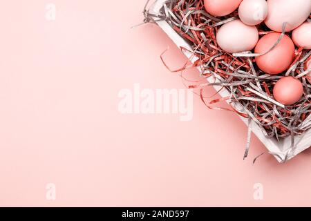 Eggs in a white tray. Creative Easter concept. Modern solid pink background. Horizontal. Living coral theme - color of the year 2019 Stock Photo