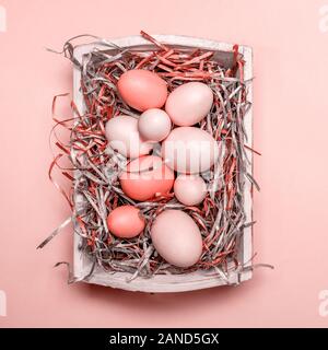 Eggs in a white tray. Creative Easter concept. Modern solid pink background. Horizontal. Living coral theme - color of the year 2019 Stock Photo