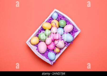 Multicolor eggs in a white tray. Creative Easter concept. Modern solid pink background. Horizontal. Living coral theme - color of the year 2019 Stock Photo
