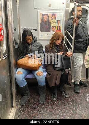 People constantly are on their cell phones when riding the subway trains in New York City Stock Photo