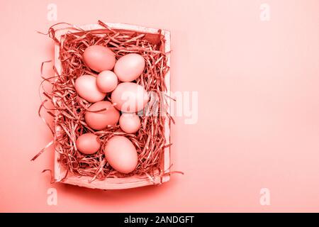 Eggs in a white tray. Creative Easter concept. Modern solid pink background. Horizontal. Living coral theme - color of the year 2019 Stock Photo