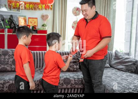 Asian father give ang pao to her son Stock Photo