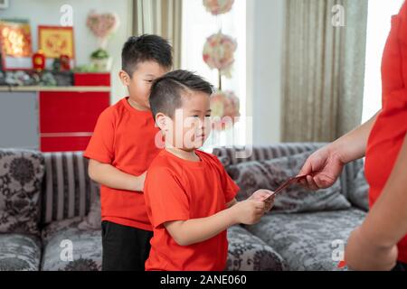 Asian chinese father give ang pao to her sons Stock Photo