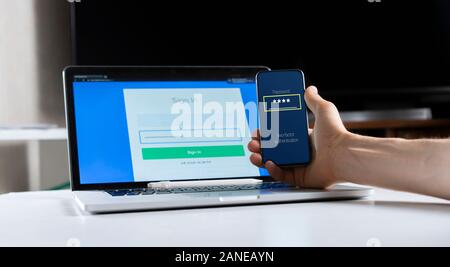 holding a phone and working using laptop, log in on website, double-factor authentication interface Stock Photo