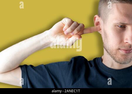 stop that noise! the male feels bad and closes his ear with his hand Stock Photo