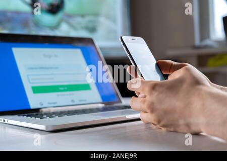 holding a phone and working using laptop, log in on website, double-factor authentication interface Stock Photo