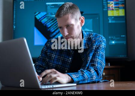 the male photographer sitting at the table working on computer, using software application Stock Photo