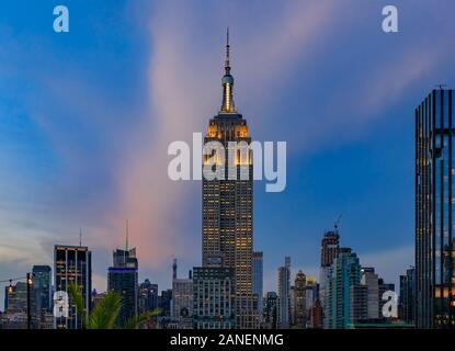 New York, USA - July 29, 2019: Manhattan downtown skyline with illuminated Empire State Building and skyscrapers at sunset