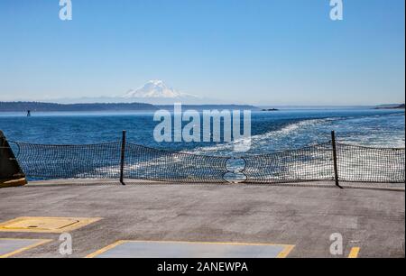 A view from on a Washington State Ferry looking out the back on the car deck at Mount Rainier and the Puget Sound, Washington, USA. Stock Photo