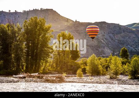 A hot air balloon floats above the Methow River in the early morning light between Twisp and Winthrop, Washington, USA. Stock Photo