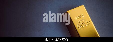 An ingot of gold metal bullion of pure brilliant diagonally located on a blue textured background Stock Photo