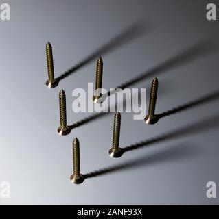 Screws arranged in a pattern, with their shadows pointing in a certain way. Stock Photo