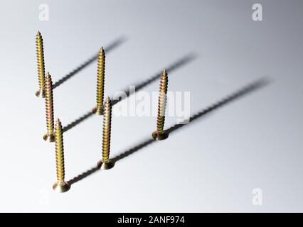 Screws arranged in a pattern, with their shadows pointing in a certain way. Stock Photo