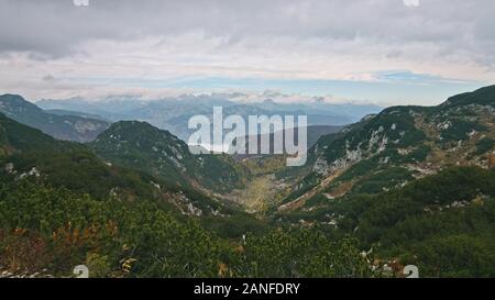 Epic view of valley in misty mountains range bakground from top. Picturesque clouds landscape. Travel Vacation Nature Concept. Stock Photo