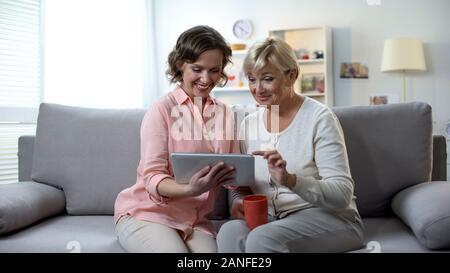 Caucasian woman with elderly mother using tablet, easy payment application Stock Photo