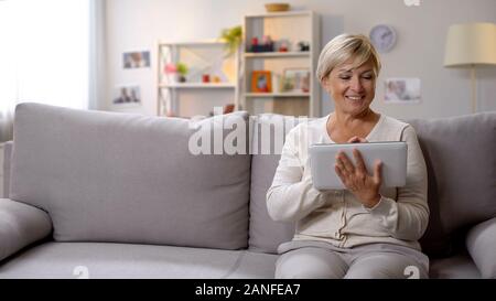 Happy mature woman using tablet, tariff payments online, banking operations Stock Photo
