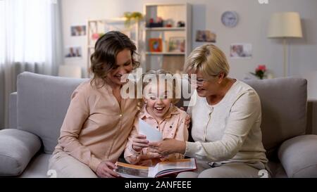 Cheerful female family viewing photo album and smiling, good memories, fun Stock Photo