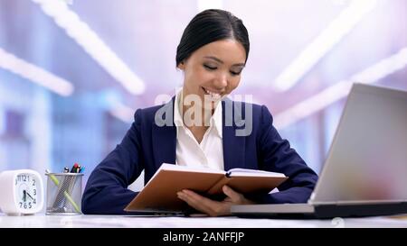 Young female employee writing in notebook, planning work day, ideas, discipline Stock Photo