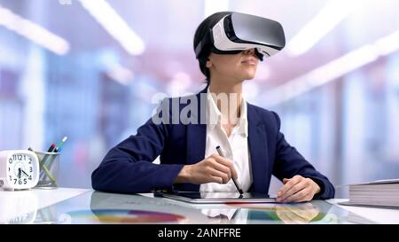 Creative graphic designer in vr goggles drawing tablet in office, modern device Stock Photo