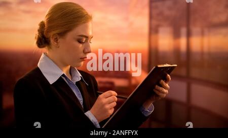 Employee checking documents, working in sunset time, dedication to favorite case Stock Photo