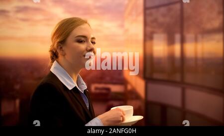 Pretty lady drinking tea, enjoying sunset at end of working day, antistress Stock Photo
