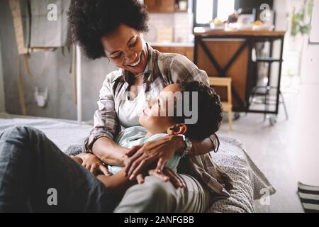 Happy mother playing, having fun, hugging with her son at home Stock Photo