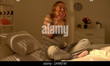 Stressed pregnant girl greedily eating donut suffering mental overload breakdown Stock Photo