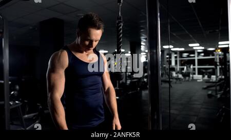 Strong man preparing for arm muscles workout, triceps cable pushdown exercise Stock Photo