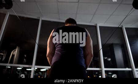 Sportsman performing chest muscles workout on cable machine in the evening Stock Photo